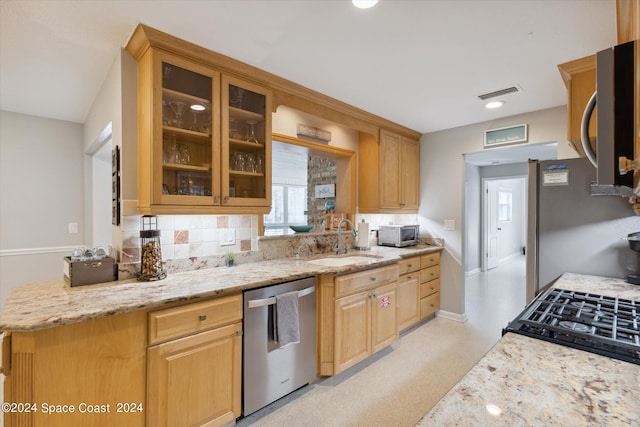 kitchen with light stone countertops, sink, stainless steel appliances, and tasteful backsplash