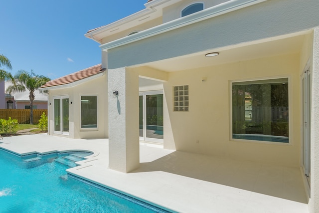 back of property featuring a patio and a fenced in pool