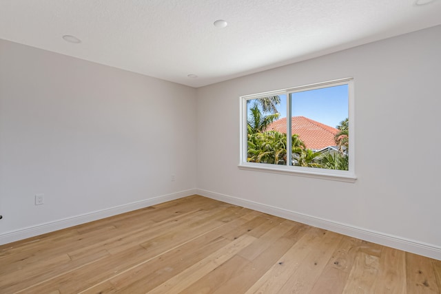 unfurnished room with a textured ceiling and light hardwood / wood-style floors