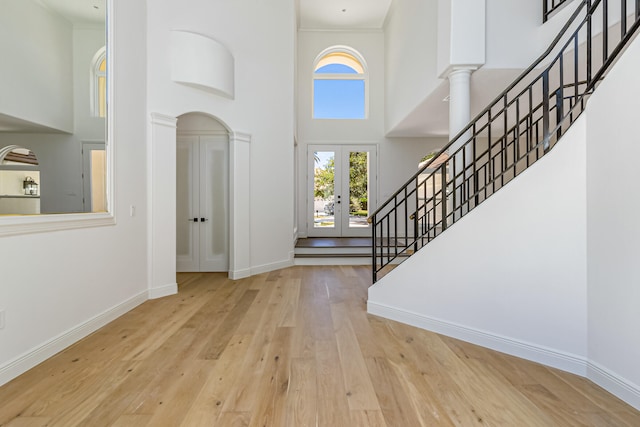 entrance foyer with a high ceiling, light hardwood / wood-style floors, french doors, and ornate columns