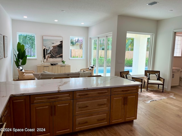 kitchen with light stone counters, a textured ceiling, and light wood-type flooring