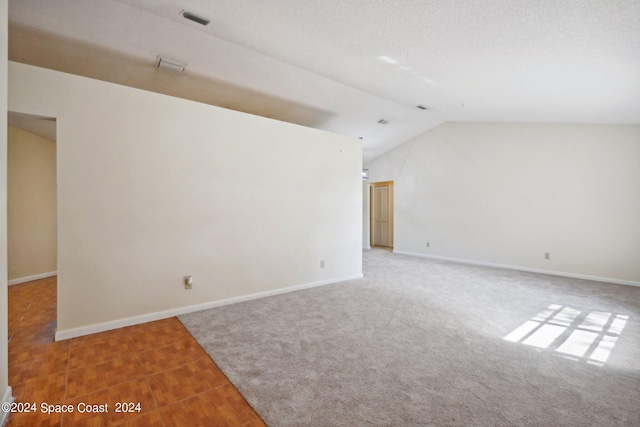 carpeted empty room with vaulted ceiling