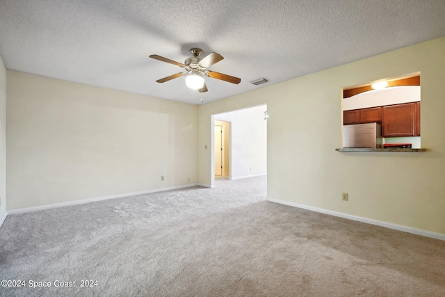 unfurnished living room featuring ceiling fan, light colored carpet, and a textured ceiling