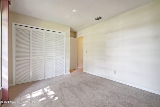 unfurnished bedroom with light carpet, a closet, and a textured ceiling