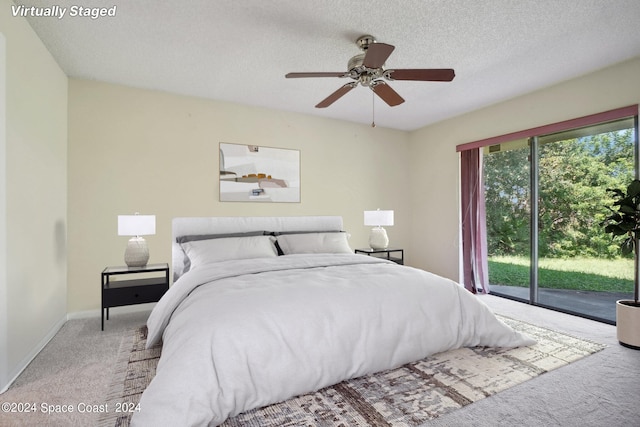 carpeted bedroom with ceiling fan, access to outside, and a textured ceiling