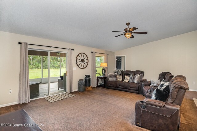 carpeted living room with a textured ceiling, vaulted ceiling, and ceiling fan