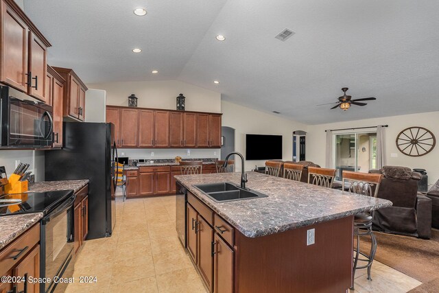 kitchen featuring a breakfast bar, sink, vaulted ceiling, black appliances, and ceiling fan