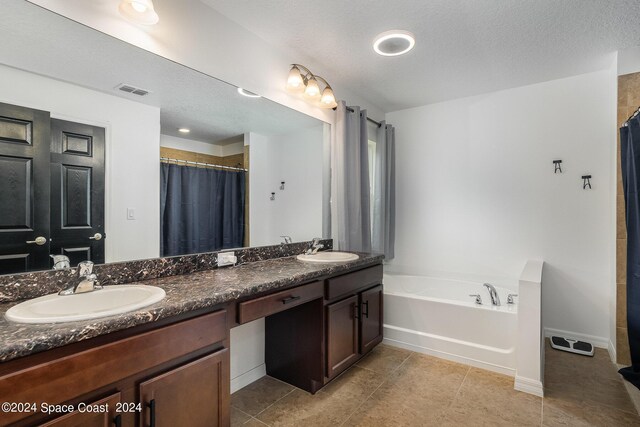 bathroom featuring vanity, tile patterned flooring, a textured ceiling, and a tub