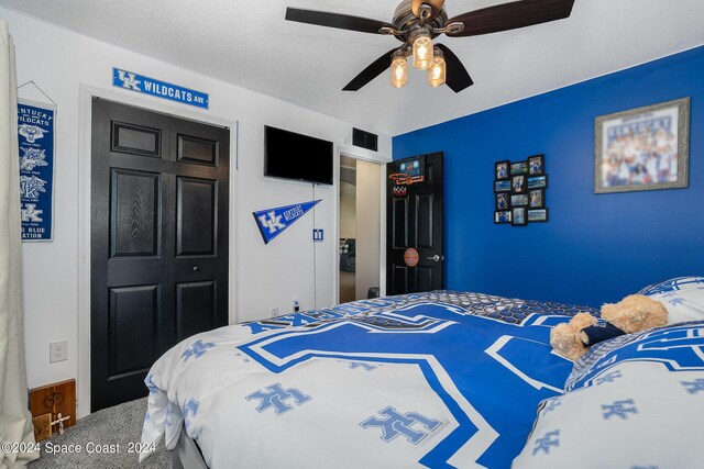 carpeted bedroom with a textured ceiling, ceiling fan, and a closet