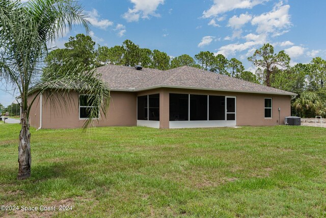 rear view of house featuring a lawn, a sunroom, and central AC unit