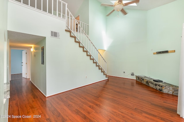 interior space with a towering ceiling, a textured ceiling, dark hardwood / wood-style floors, and ceiling fan