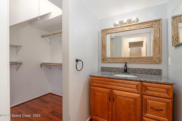 bathroom with a textured ceiling, hardwood / wood-style flooring, and vanity