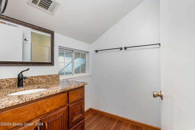 bathroom featuring wood-type flooring, vaulted ceiling, and vanity