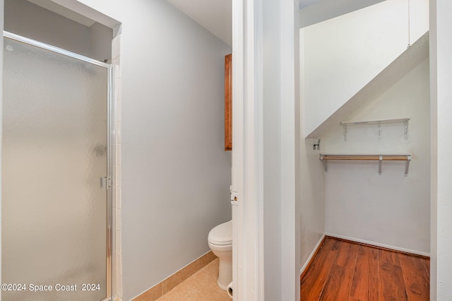 bathroom featuring hardwood / wood-style flooring, toilet, and a shower with door