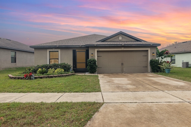 view of front of home featuring central AC unit, a garage, and a yard