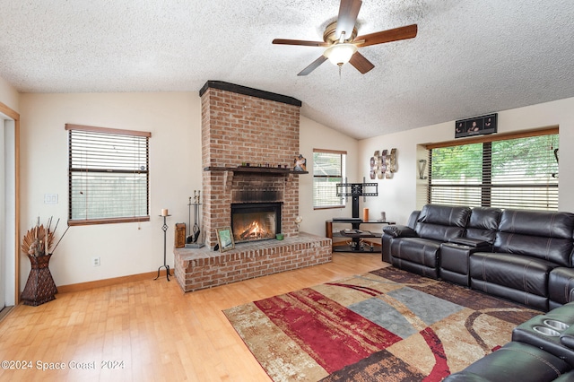 living room with a fireplace, a textured ceiling, hardwood / wood-style floors, vaulted ceiling, and ceiling fan