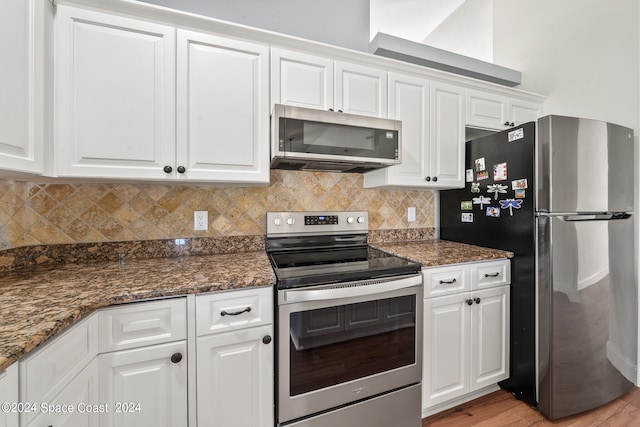 kitchen featuring dark stone counters, stainless steel appliances, white cabinets, and light hardwood / wood-style floors