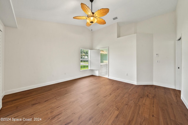 empty room featuring a high ceiling, dark hardwood / wood-style flooring, and ceiling fan