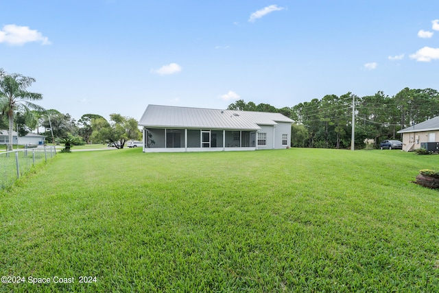 rear view of house with a lawn and a sunroom