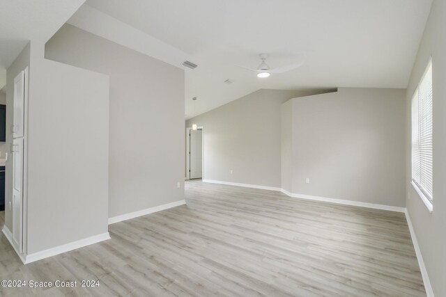 spare room featuring light wood-type flooring, vaulted ceiling, and ceiling fan