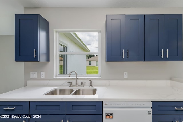 kitchen featuring blue cabinets, white dishwasher, and sink