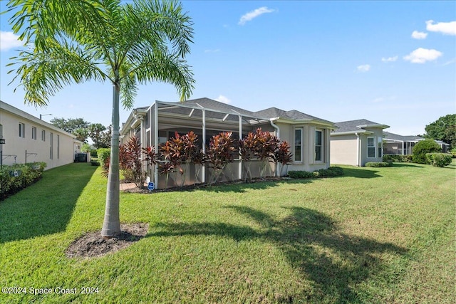 back of house featuring a lanai and a yard