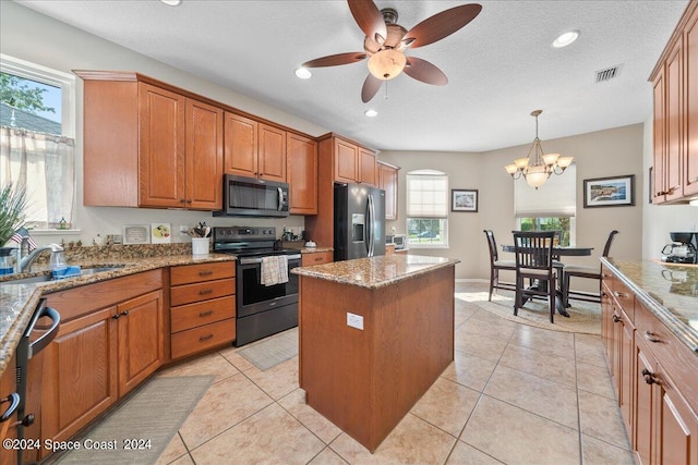 kitchen with pendant lighting, sink, a kitchen island, stainless steel appliances, and ceiling fan with notable chandelier