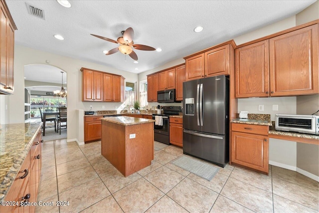 kitchen featuring a kitchen island, black appliances, ceiling fan with notable chandelier, and a wealth of natural light