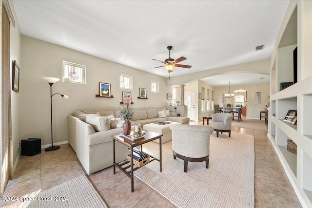 living room with a textured ceiling, ceiling fan with notable chandelier, and light tile patterned floors