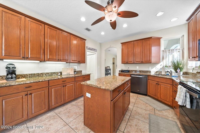 kitchen with light stone counters, light tile patterned flooring, a kitchen island, appliances with stainless steel finishes, and ceiling fan