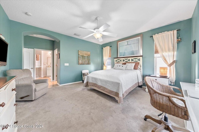 bedroom featuring light colored carpet, a textured ceiling, ceiling fan, and ensuite bathroom