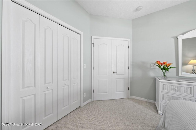 bedroom featuring light carpet and a textured ceiling