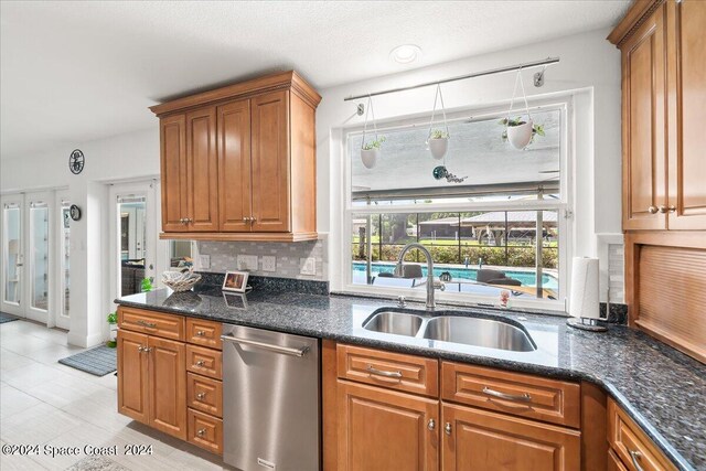 kitchen with tasteful backsplash, dishwasher, sink, and dark stone counters