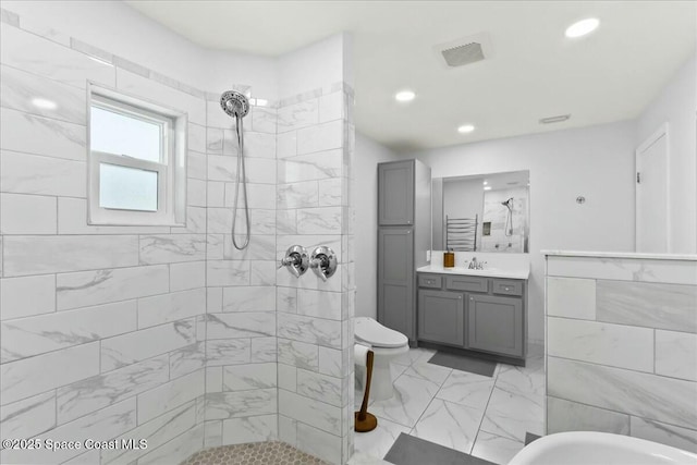 bathroom with vanity, a tile shower, and tile walls