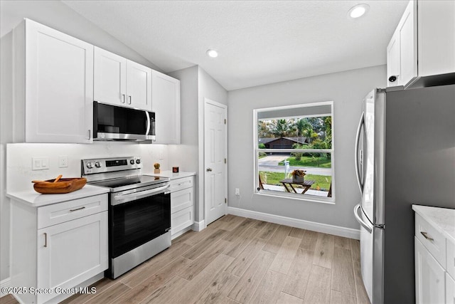 kitchen with baseboards, white cabinets, appliances with stainless steel finishes, light countertops, and light wood-style floors