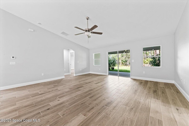 unfurnished living room with arched walkways, a ceiling fan, baseboards, vaulted ceiling, and light wood finished floors