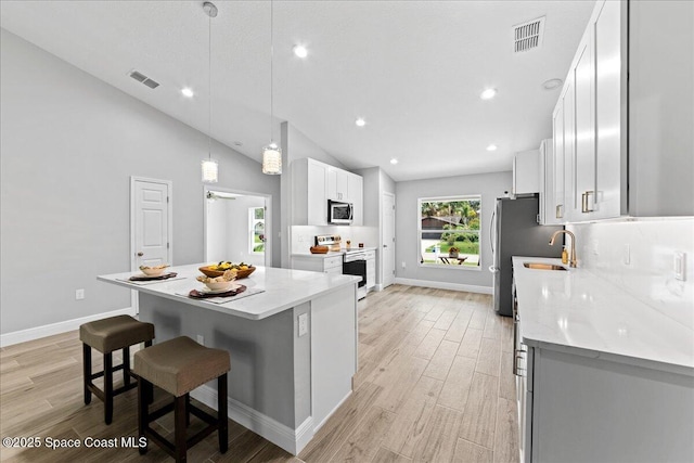 kitchen with stainless steel appliances, visible vents, white cabinets, a center island, and pendant lighting