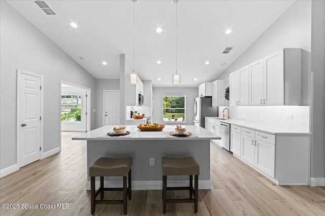 kitchen with light countertops, appliances with stainless steel finishes, decorative light fixtures, and white cabinets