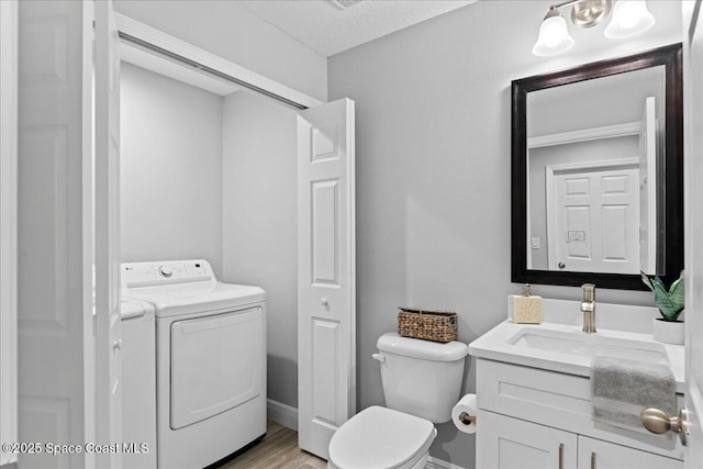 bathroom featuring toilet, wood finished floors, vanity, a closet, and independent washer and dryer