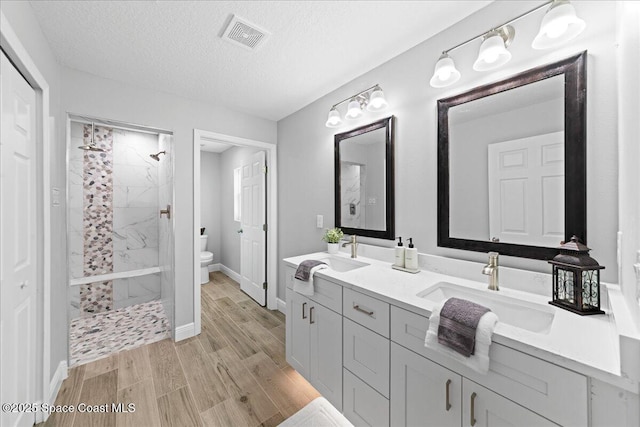 bathroom featuring double vanity, visible vents, a sink, and wood finished floors