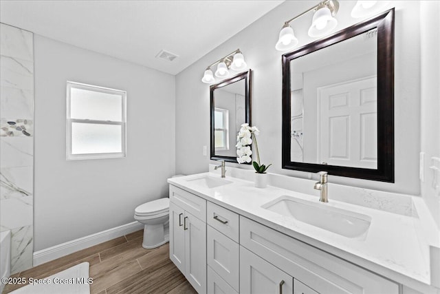 full bathroom with double vanity, wood finished floors, a sink, and visible vents