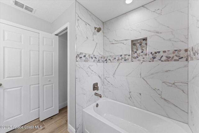 full bath featuring baseboards, visible vents, shower / washtub combination, and wood finished floors