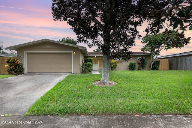 single story home featuring a garage and a yard