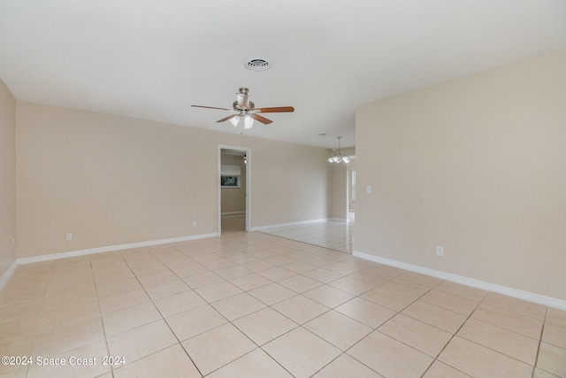 spare room featuring light tile patterned flooring and ceiling fan with notable chandelier