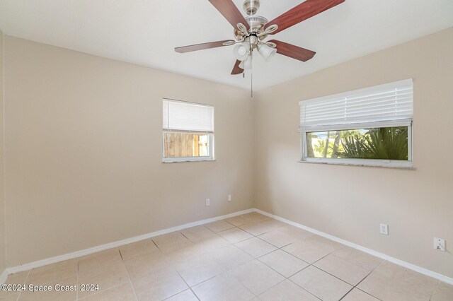 tiled empty room with ceiling fan and a wealth of natural light