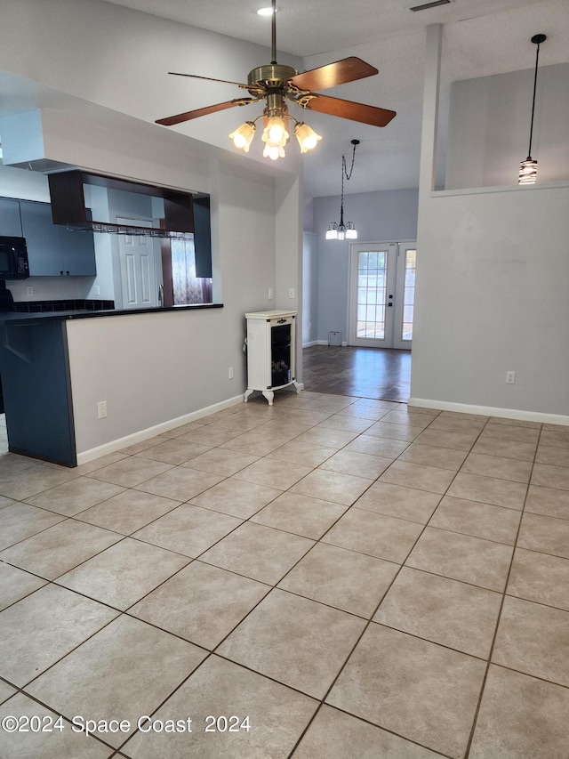 kitchen with hanging light fixtures, ceiling fan with notable chandelier, lofted ceiling, and light tile patterned floors