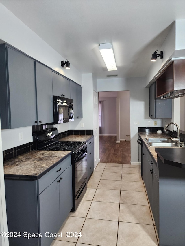 kitchen featuring light wood-type flooring, black appliances, gray cabinetry, and sink