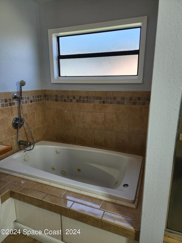 bathroom with a relaxing tiled tub and a wealth of natural light