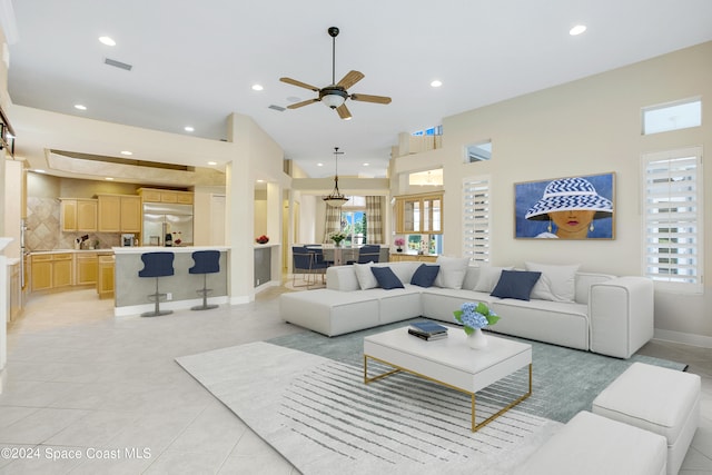 tiled living room with ceiling fan and a high ceiling