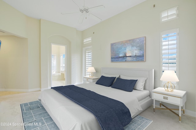 carpeted bedroom with ceiling fan, multiple windows, and ensuite bath